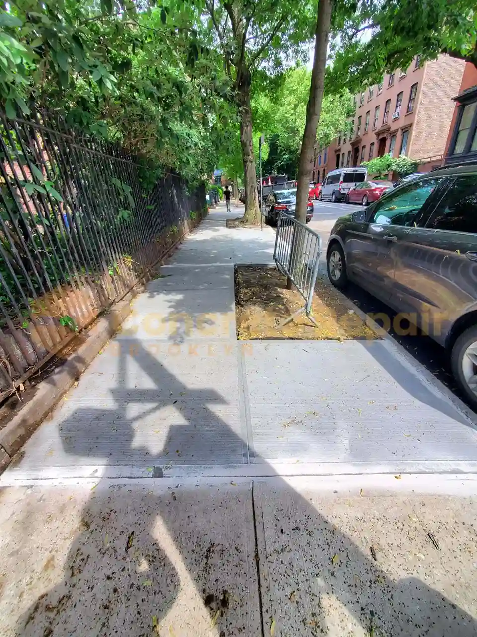 A dry concrete sidewalk section bordered by a green chain-link fence.